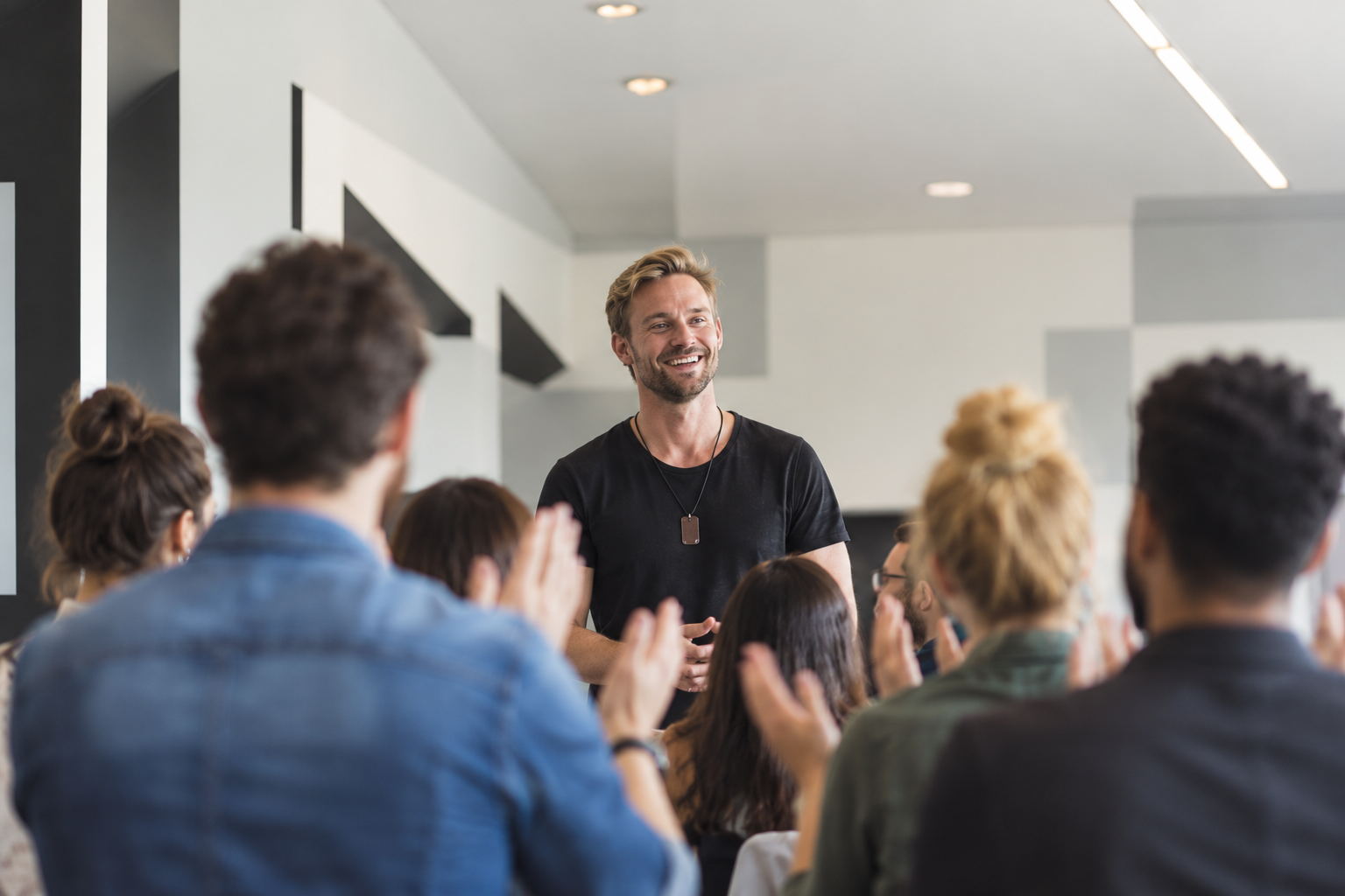 Trainer vor applaudierender Seminargruppe